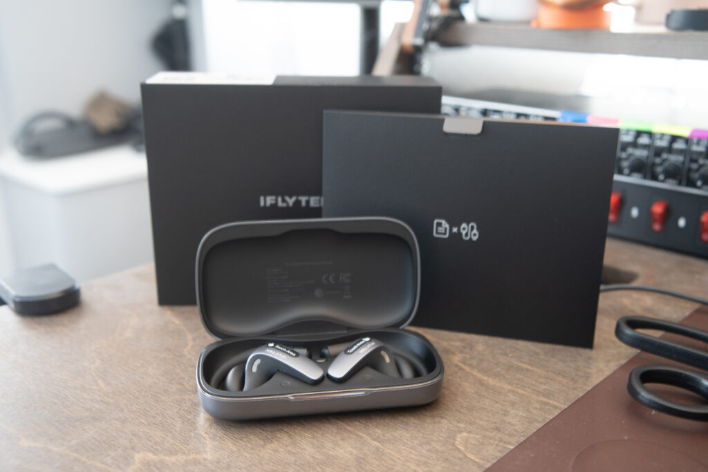 iFLYTEK AI Translation Earbuds with their accessories on a desk